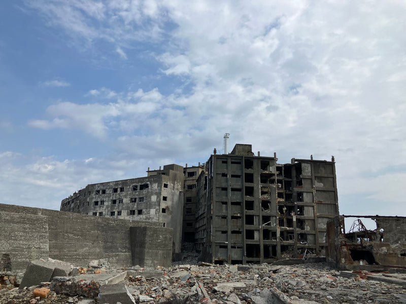 Crumbling concrete ruins of an urban building under a cloudy blue sky.