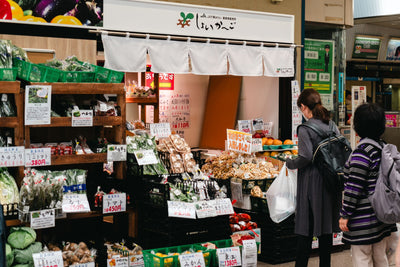 Two women shopping at a vibrant fresh produce market in Tokyo, Japan.