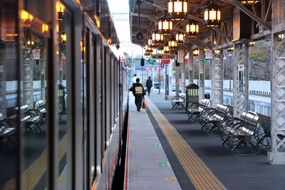 Commuters on a train platform in Kyoto, Japan, with vintage lanterns lining the station.