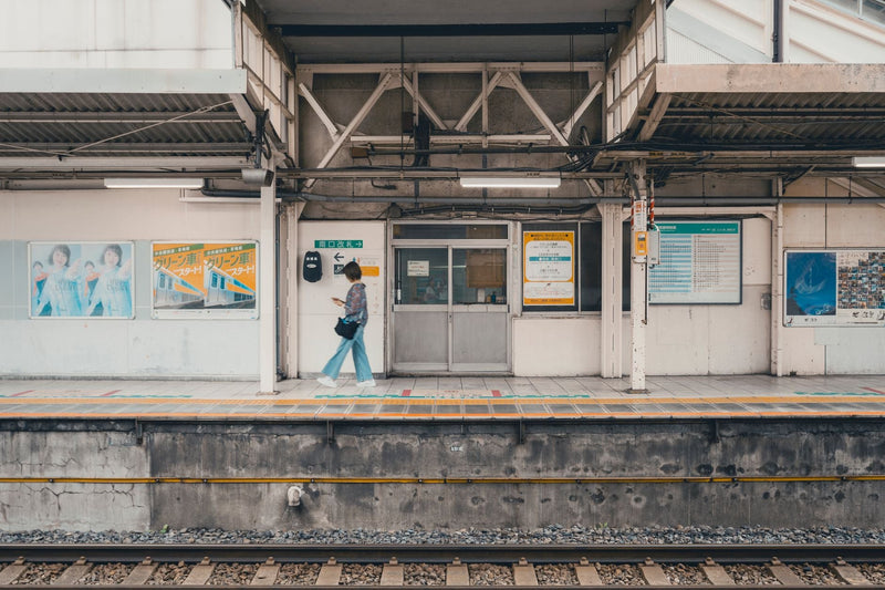 A woman walking along a train platform at a Tokyo station, showcasing the station's architecture and mood.