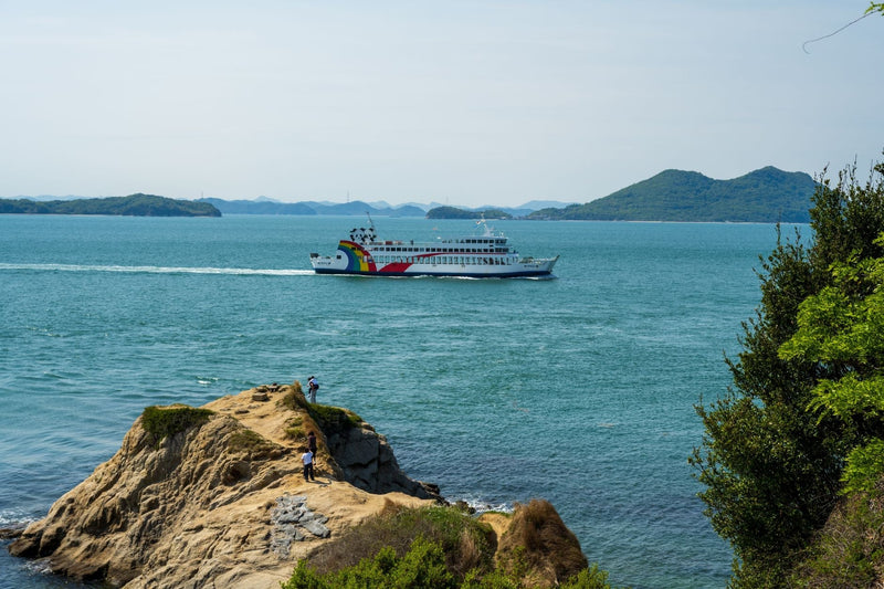 A vibrant ferry sails past a coastal cliff, offering stunning ocean views and scenic island background.