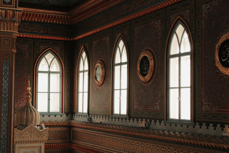 Intricately designed mosque interior featuring tall arched windows and detailed wall patterns.