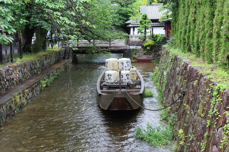 Traditional Japanese boat with sake barrels cruising a serene canal in Kyoto, Japan.