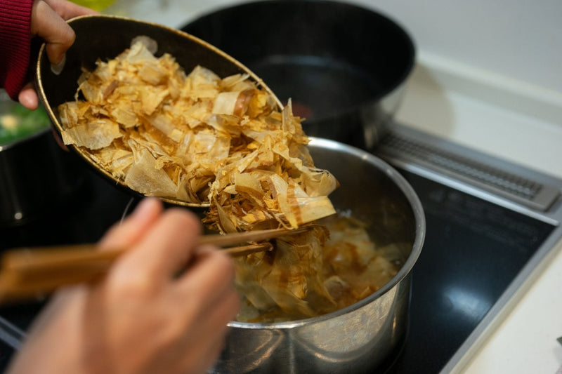 Cooking Japanese dashi stock with bonito flakes on a stove for authentic Asian cuisine.