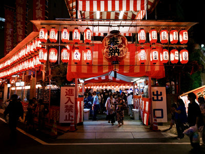 Colorful Japanese festival with lanterns and people in traditional clothing at night.