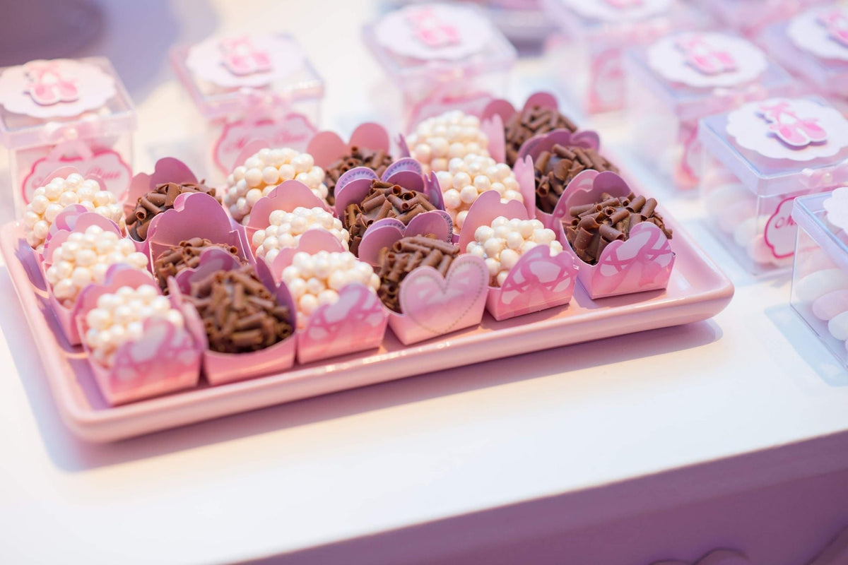 Elegant arrangement of chocolates and sweets in pink wrappers on a tray for a festive occasion.