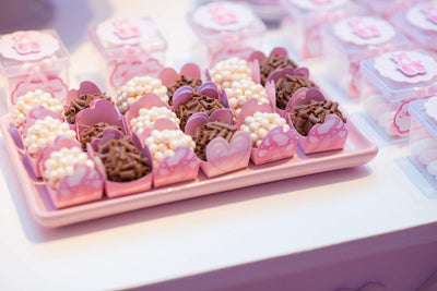 Elegant arrangement of chocolates and sweets in pink wrappers on a tray for a festive occasion.